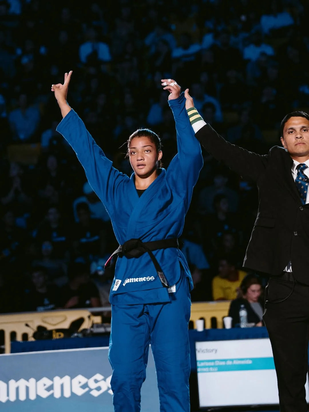 LARISSA_DIAS with a black belt stands with arms raised